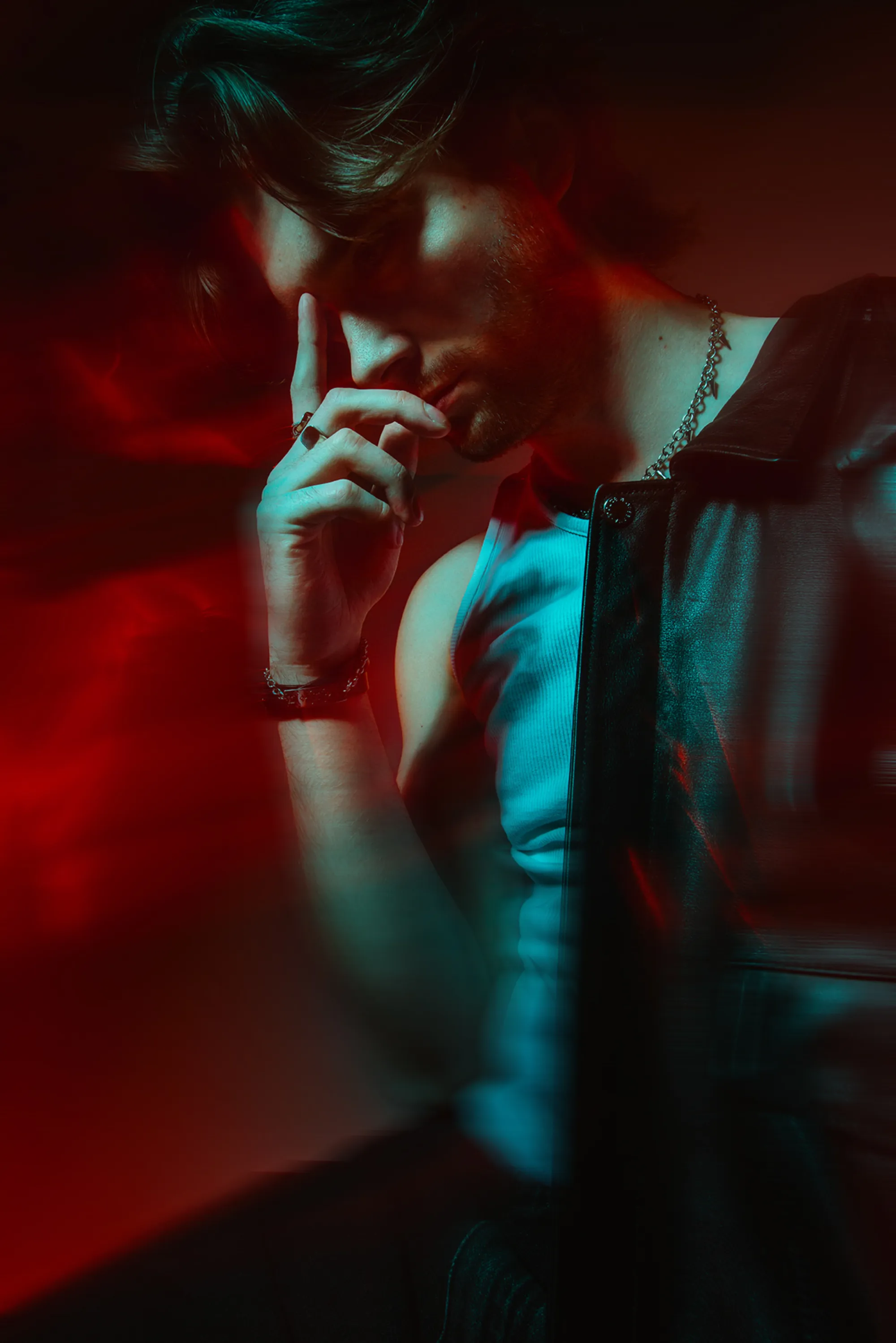 Vojtěch in red and turquoise light, finger to his lips